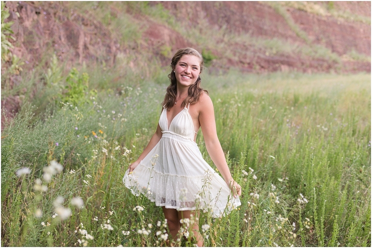 Senior photos of a girl in a white dress in a flower field