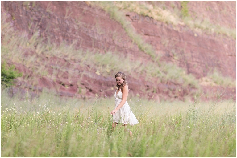 Senior photos of a girl in a white dress in a flower field