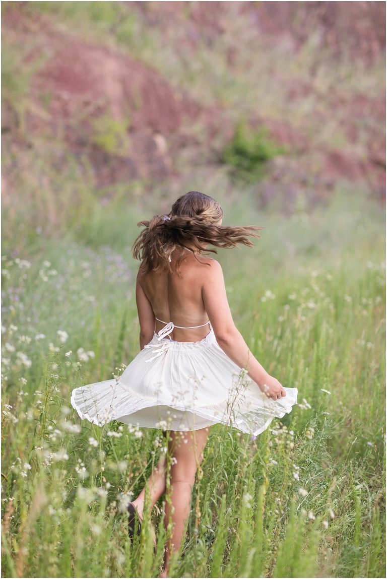 Senior photos of a girl in a white dress in a flower field