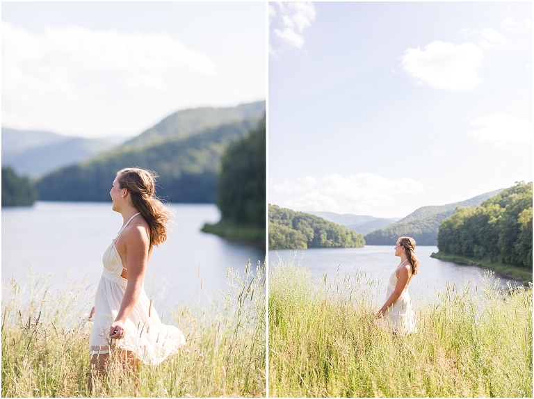 Senior photos of a girl in a white dress in a field by the lake with a mountain view taken by a Virginia graduation photographer