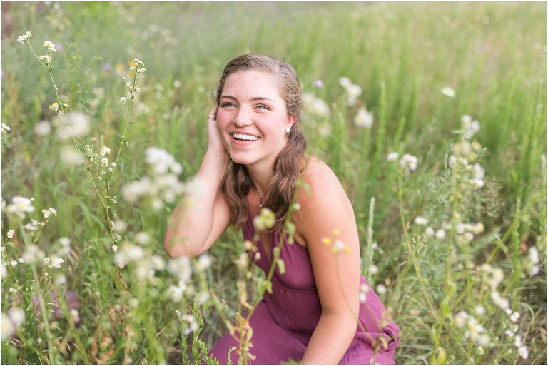 Senior photos of a girl in a purple dress in a flower field