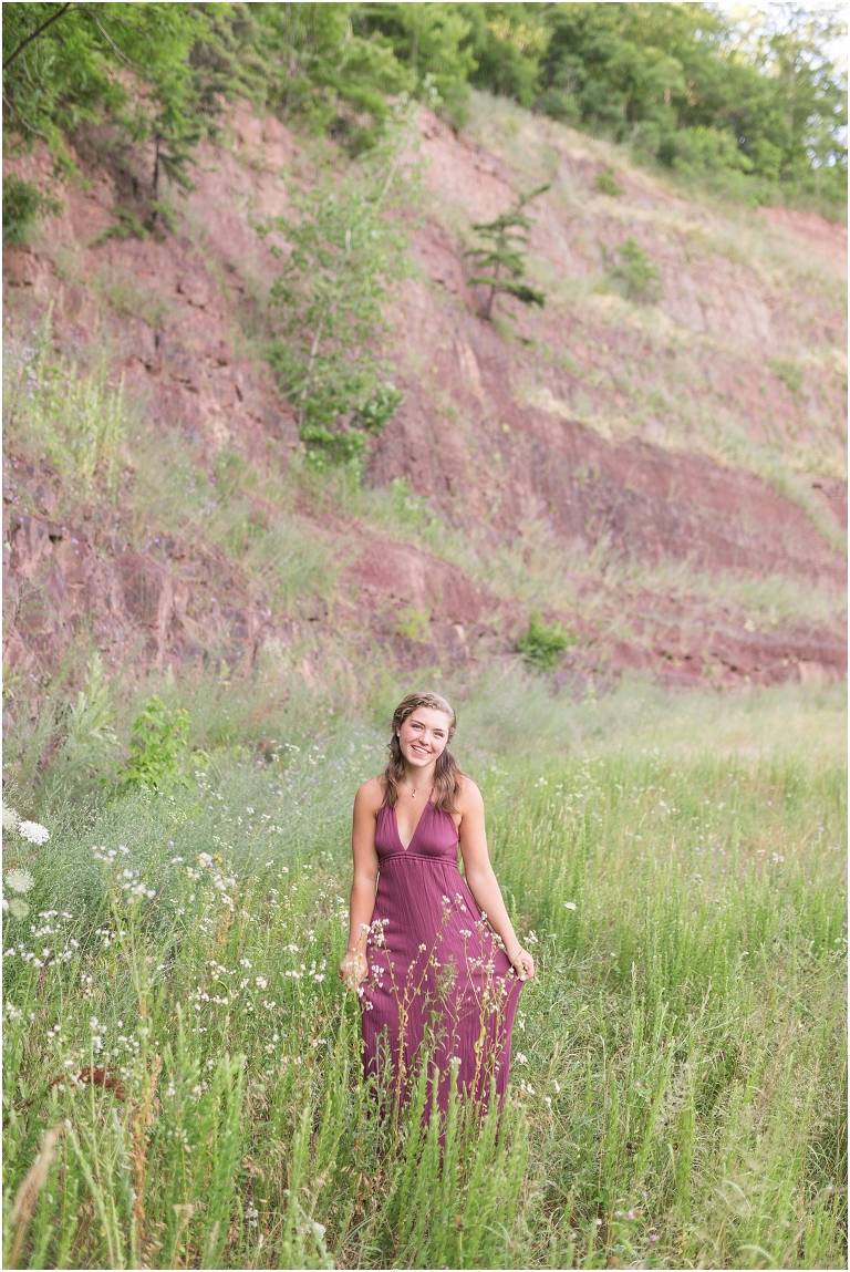 Senior photos of a girl in a purple dress in a flower field