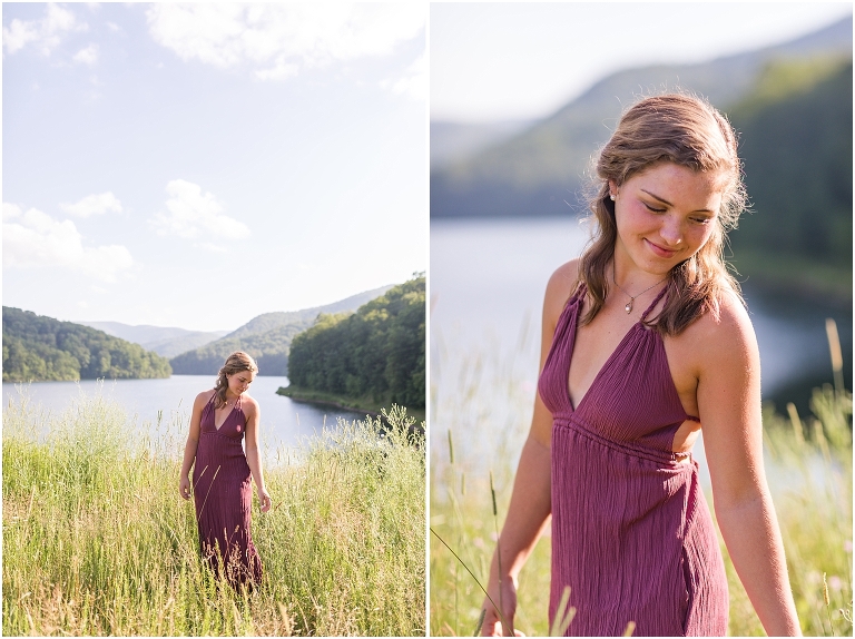Senior photos of a girl in a purple dress in a field overlooking a lake with a mountain background taken by a Virginia portrait photographer