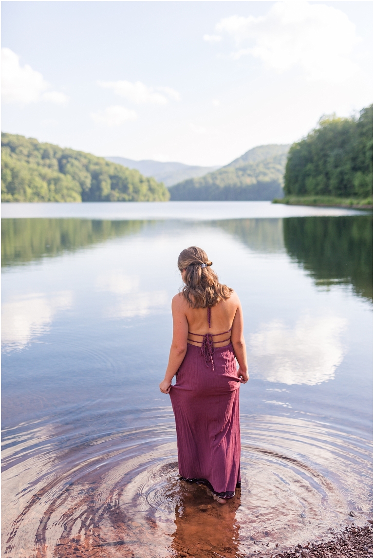 Switzer Lake senior photos of a girl in a purple dress in a lake with a mountain background taken by a Virginia portrait photographer