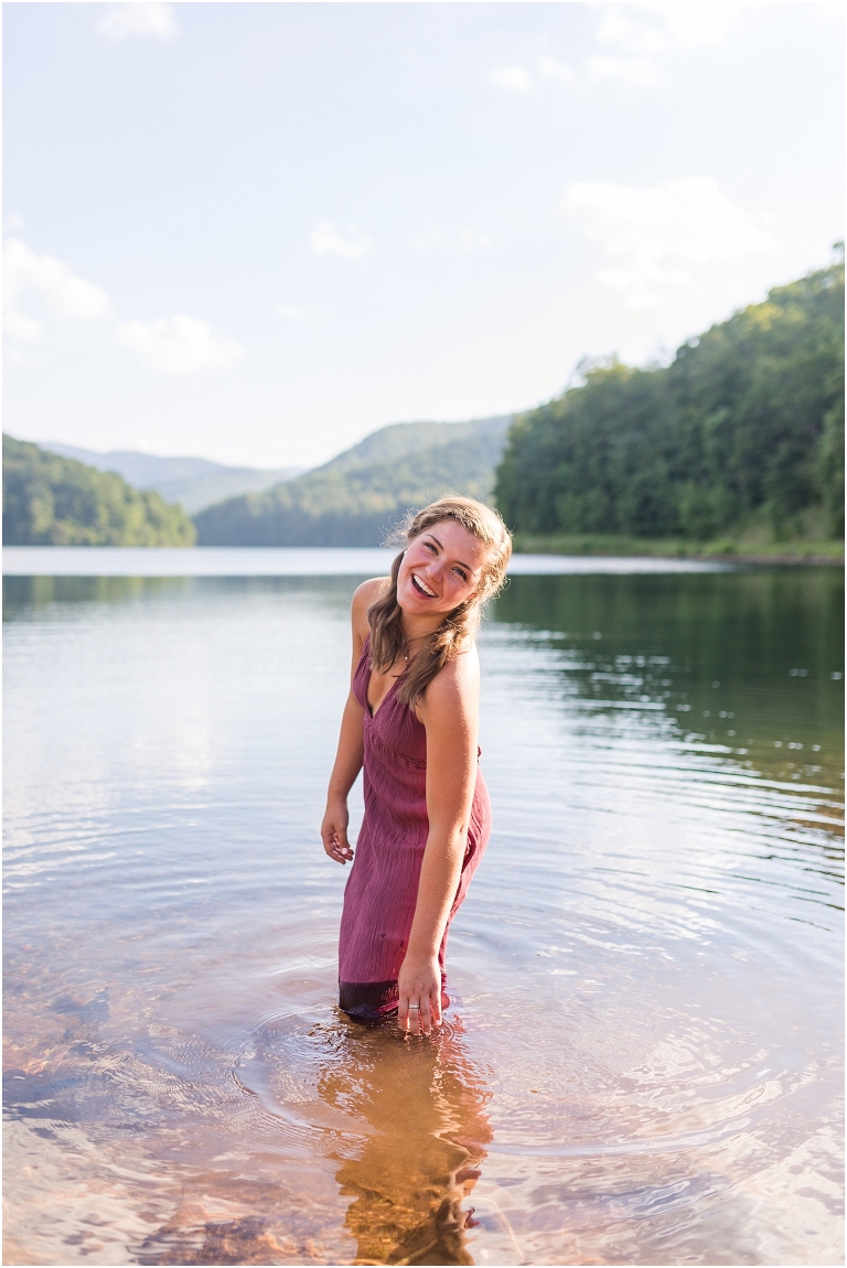 Switzer Lake senior photos of a girl in a purple dress in a lake with a mountain background taken by a Virginia portrait photographer