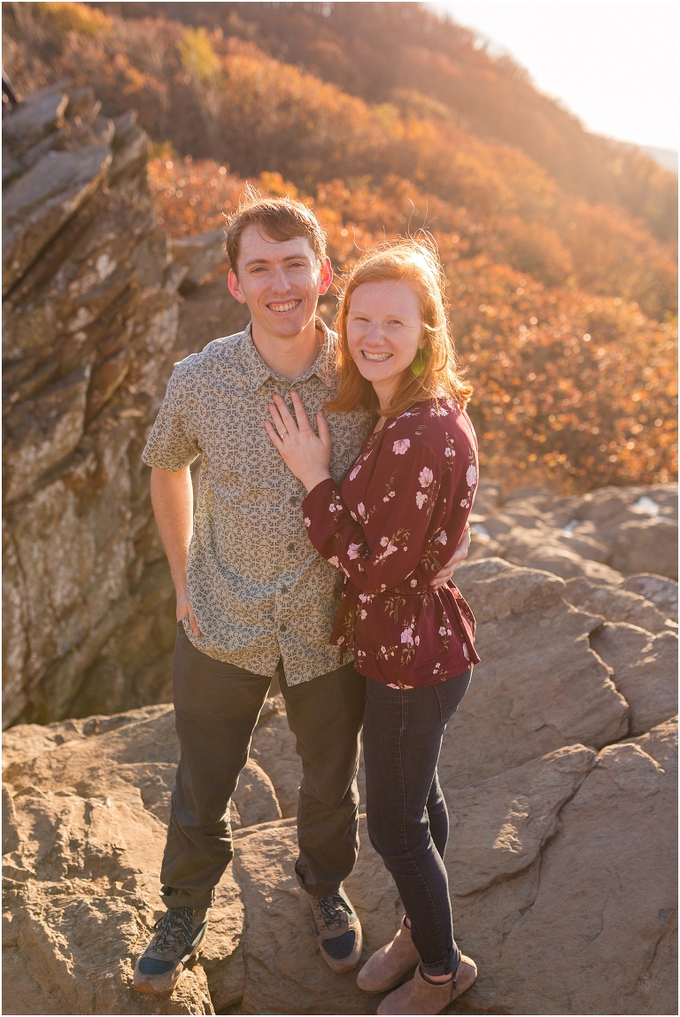 Couple at engagement session at Humpback Rocks during sunset, surrounded by fall colors and blue sky.