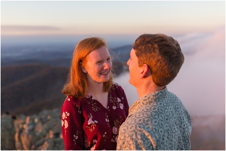 Couple at engagement session at Humpback Rocks during sunset, surrounded by fall colors, blue sky, and mountain fog.