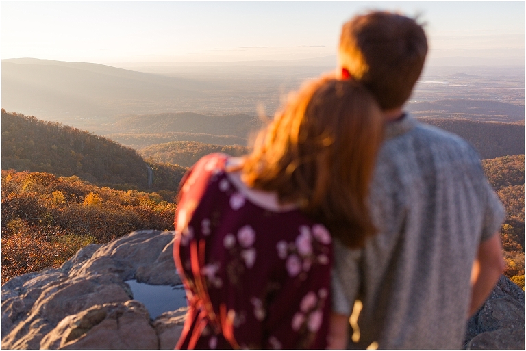 Couple at engagement session at Humpback Rocks during sunset, surrounded by fall colors, blue sky, and mountain fog.