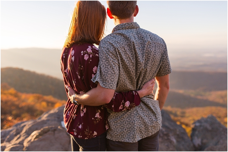 Couple at engagement session at Humpback Rocks during sunset, surrounded by fall colors, blue sky, and mountain fog.