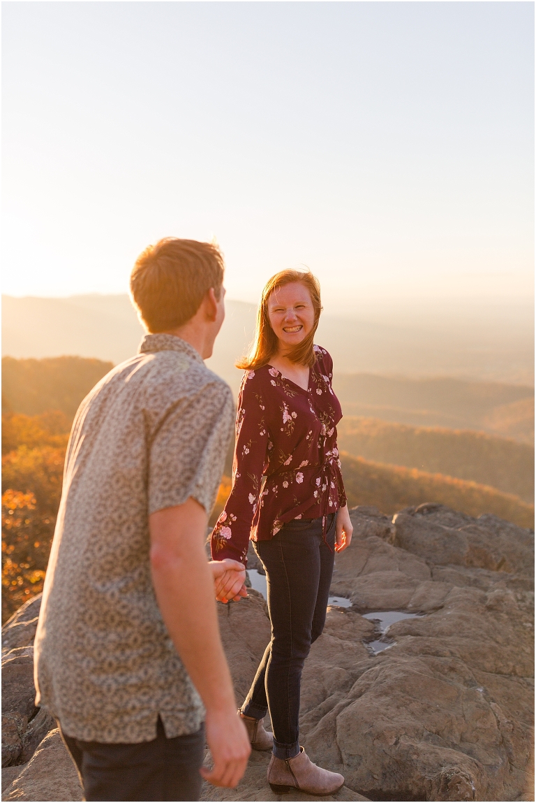 Couple at engagement session at Humpback Rocks during sunset, surrounded by fall colors, blue sky, and mountain fog.