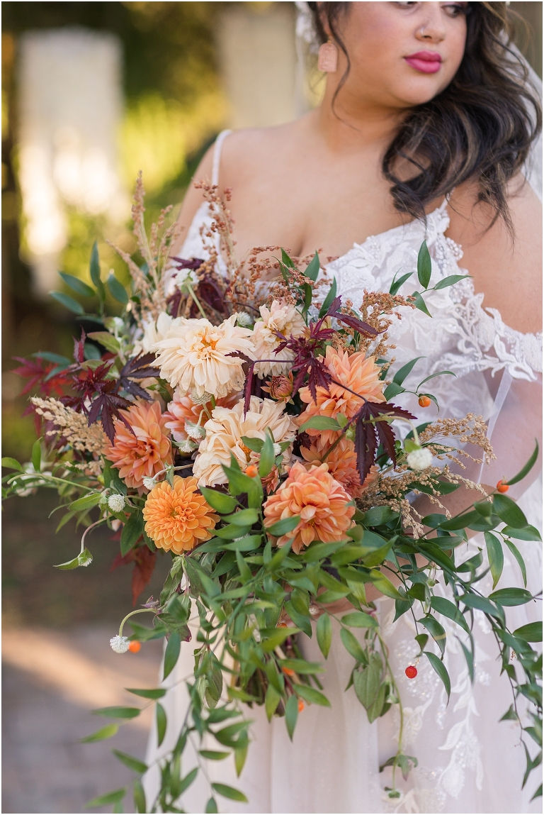 Autumn wedding inspiration color palette with bride in front of golden hour arbor holding bouquet