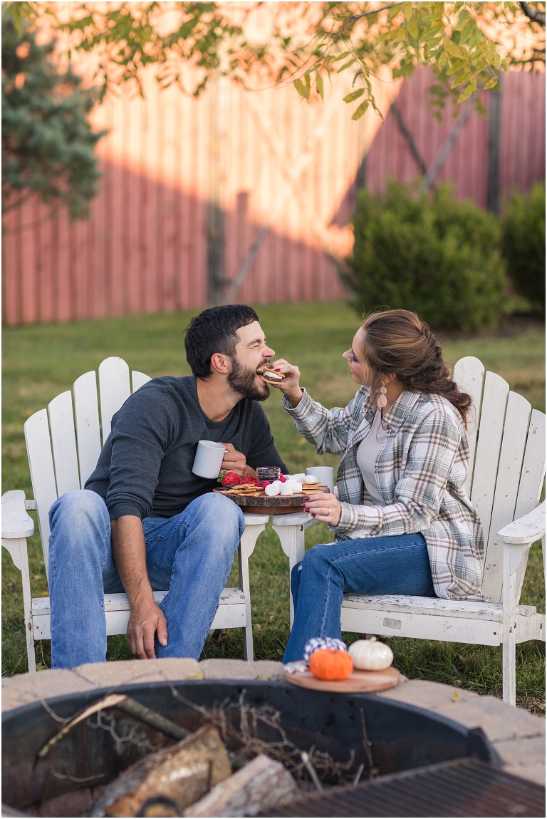 Country engagement session with couple sitting by an open fire sharing a smore's charcutier board