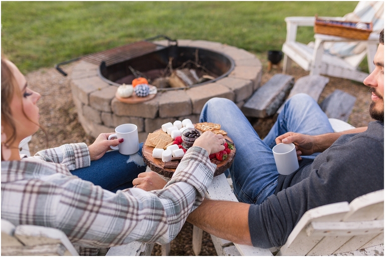 Country engagement session with couple sitting by an open fire sharing a smore's charcutier board