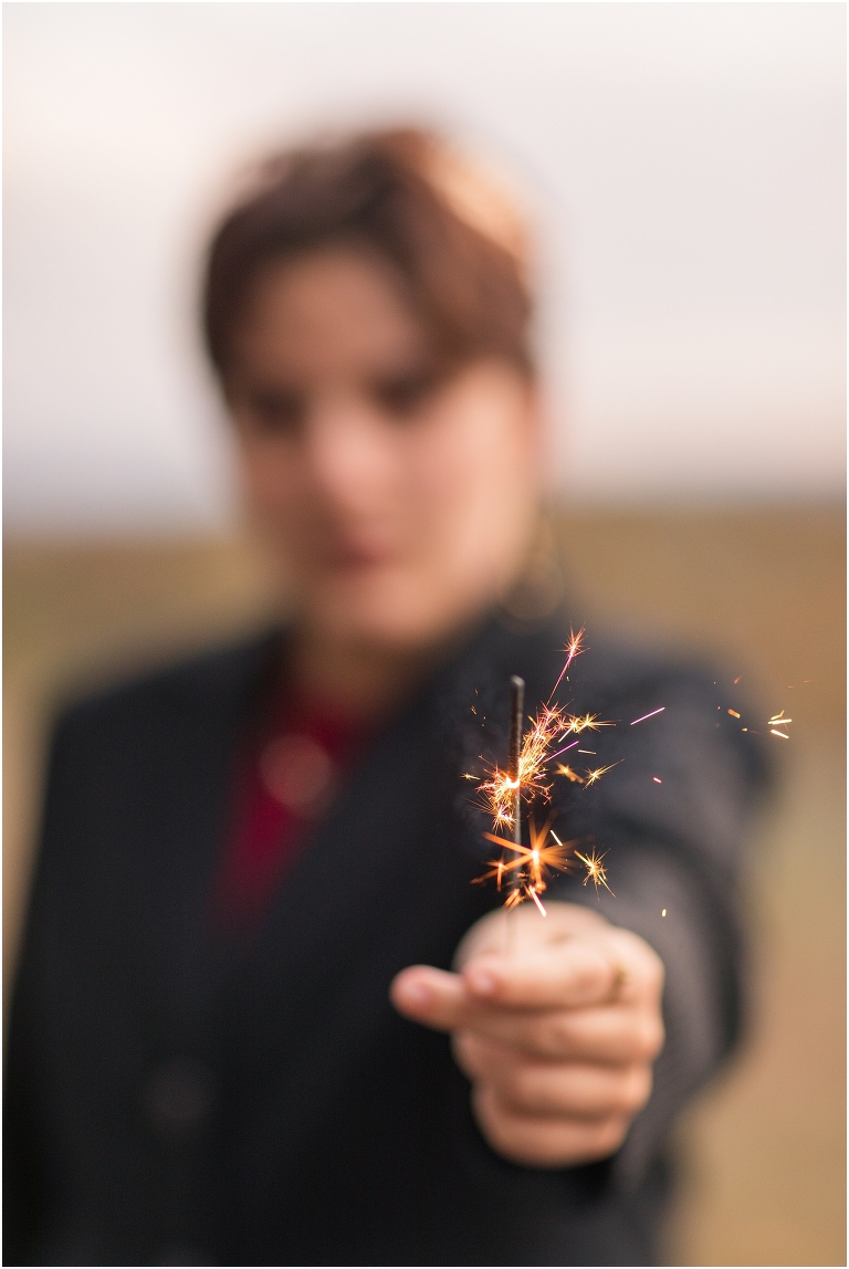 Ares Greek Mythology inspired portrait session all black suit golden crown and sparklers at the top of a hill with a sunset mountain view