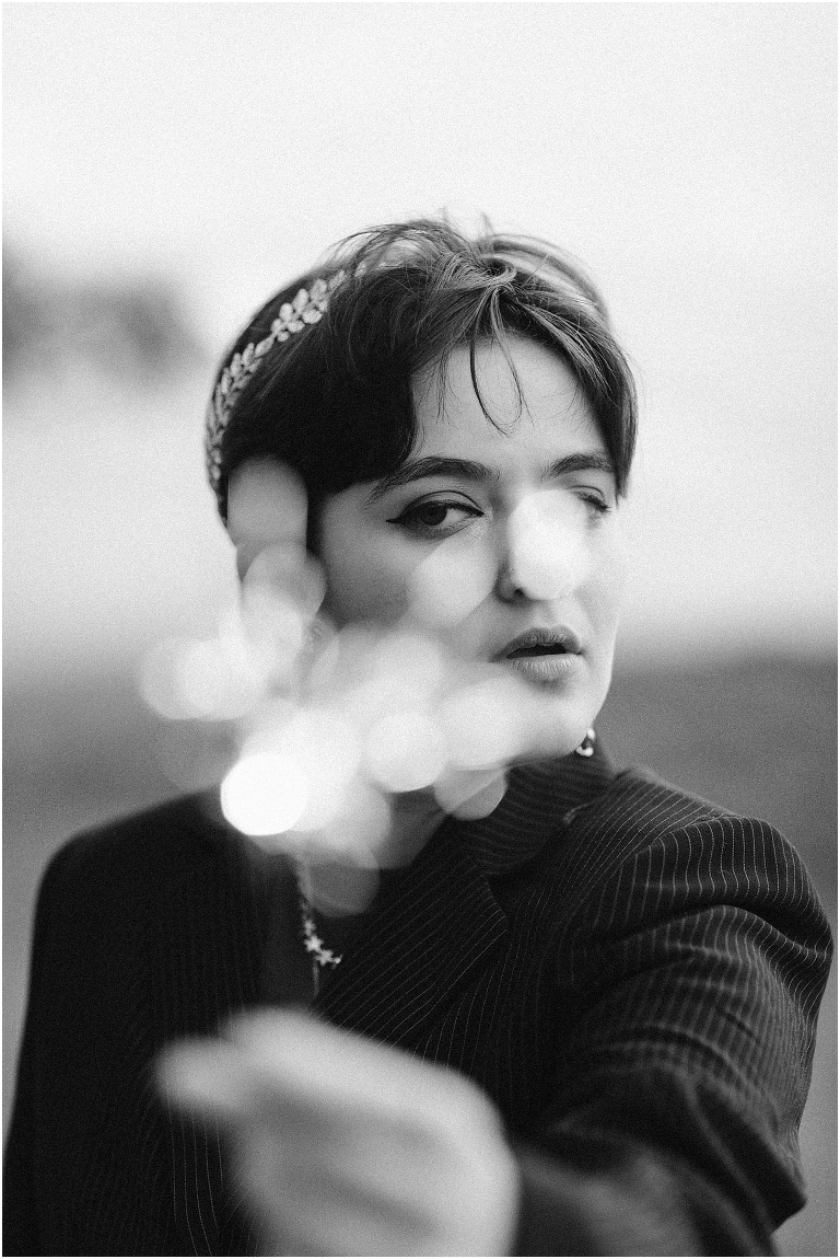 Ares Greek Mythology inspired portrait session all black suit golden crown and sparklers at the top of a hill with a sunset mountain view