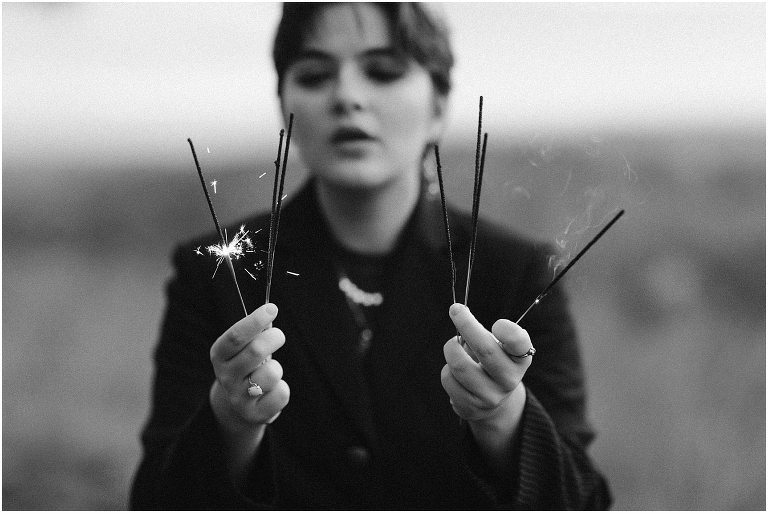 Ares Greek Mythology inspired portrait session all black suit golden crown and sparklers at the top of a hill with a sunset mountain view