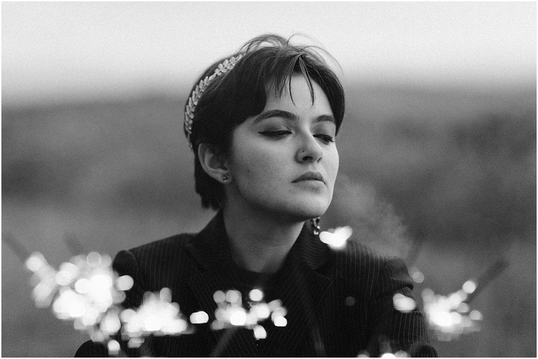 Ares Greek Mythology inspired portrait session all black suit golden crown and sparklers at the top of a hill with a sunset mountain view