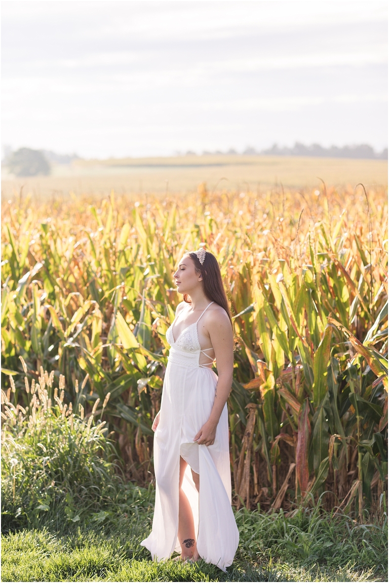 Demeter Greek Mythology goddess of agriculture inspired portrait session white dress golden crown in an open field next to corn with a sunrise mountain view
