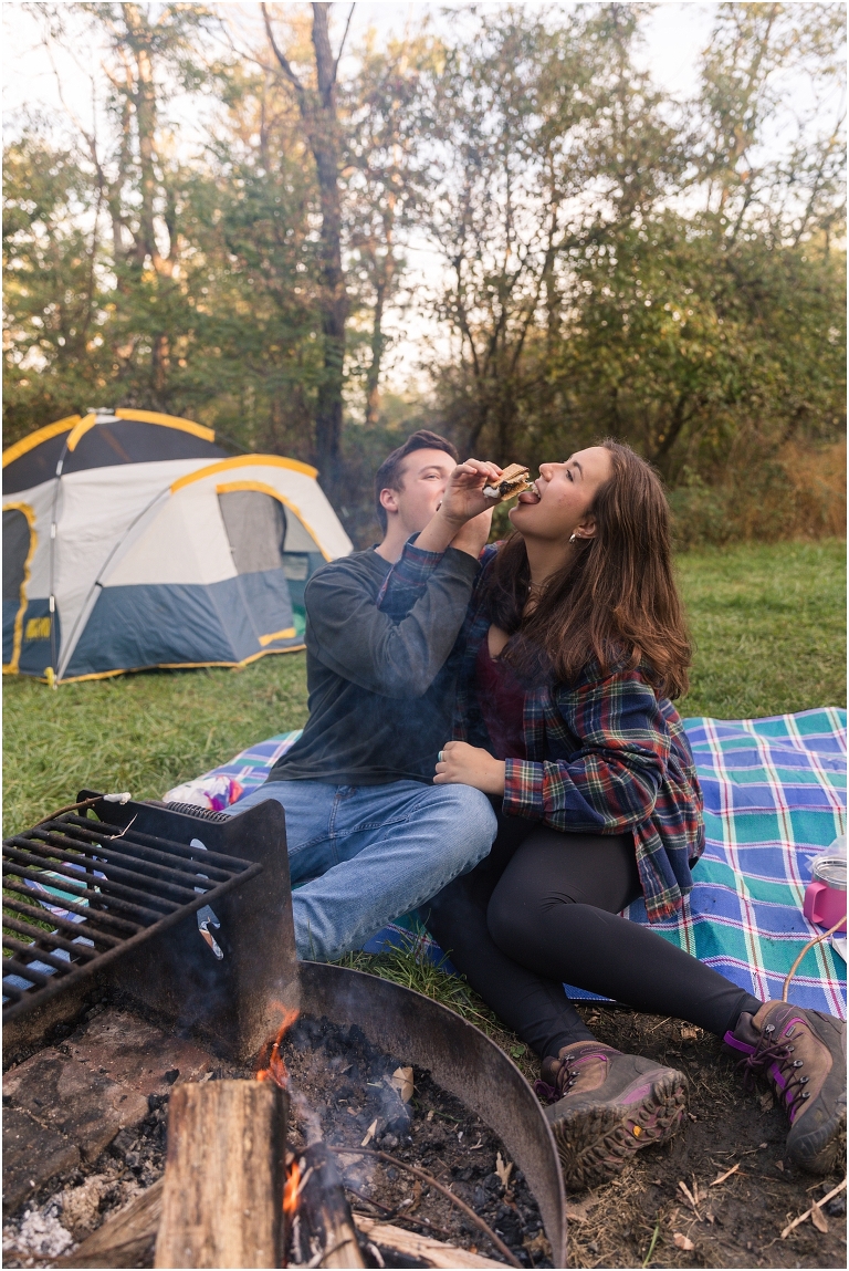 Couples camping session photos couple by a campfire eating s'mores by a tent in a campsite on Skyline Drive in Shenandoah National Park