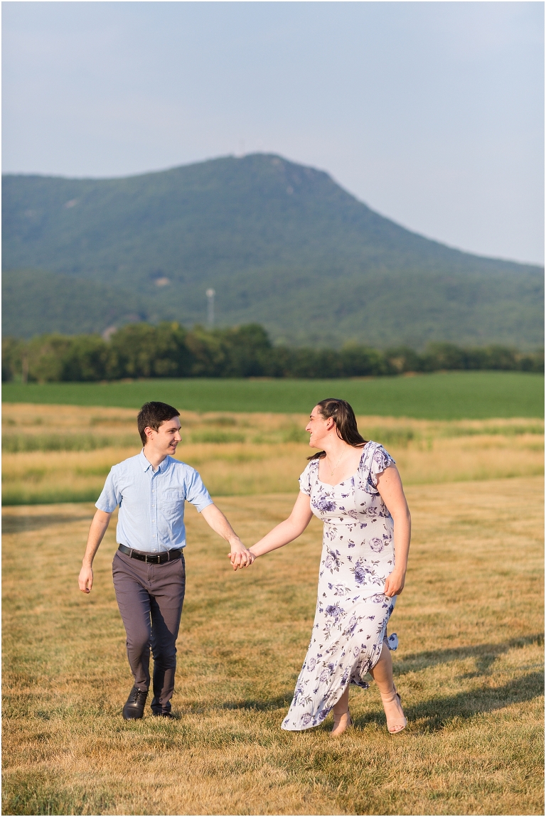 Summer couples portraits in an open field during golden hour with a mountain view