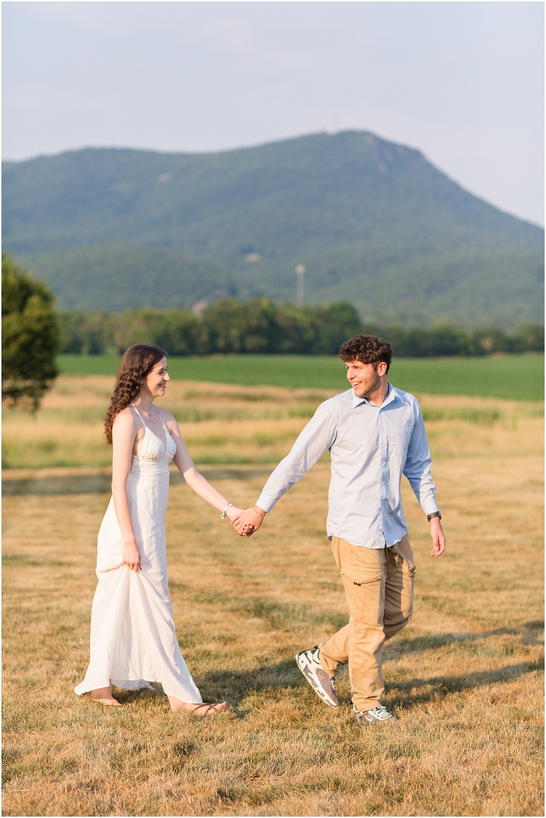 Summer couples portraits in an open field during golden hour with a mountain view