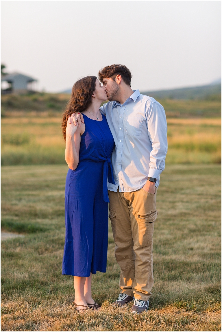 Summer couples portraits in an open field during golden hour with a mountain view