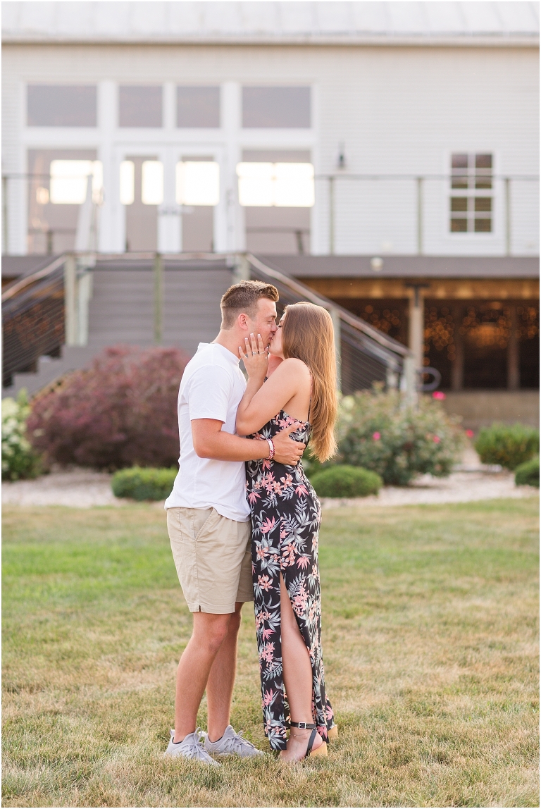 Summer couples portraits in an open field during golden hour in front of a white barn