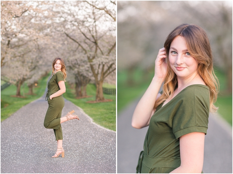 Senior portraits in a green jumpsuit on a road lined with cherry blossoms at a barn at sunset, Virginia senior graduation portrait photographer