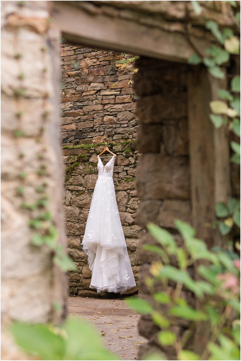 Emma & Dan's The Mill at Fine Creek Richmond autumn wedding with a riverside first look, ceremony in the garden surrounded by fall foliage, and portraits in the fairy light lit abandoned mill at dusk. This is a wedding dress photo looking through the window of the abandoned mill