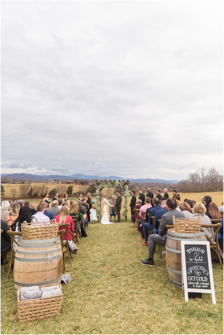Kristin & Casey's green corduroy winter white barn wedding at Renback Barn with a custom wedding name sign, mountain view wedding portraits, all black wedding party clothes, wedding jean jacket, and sparkler exit.