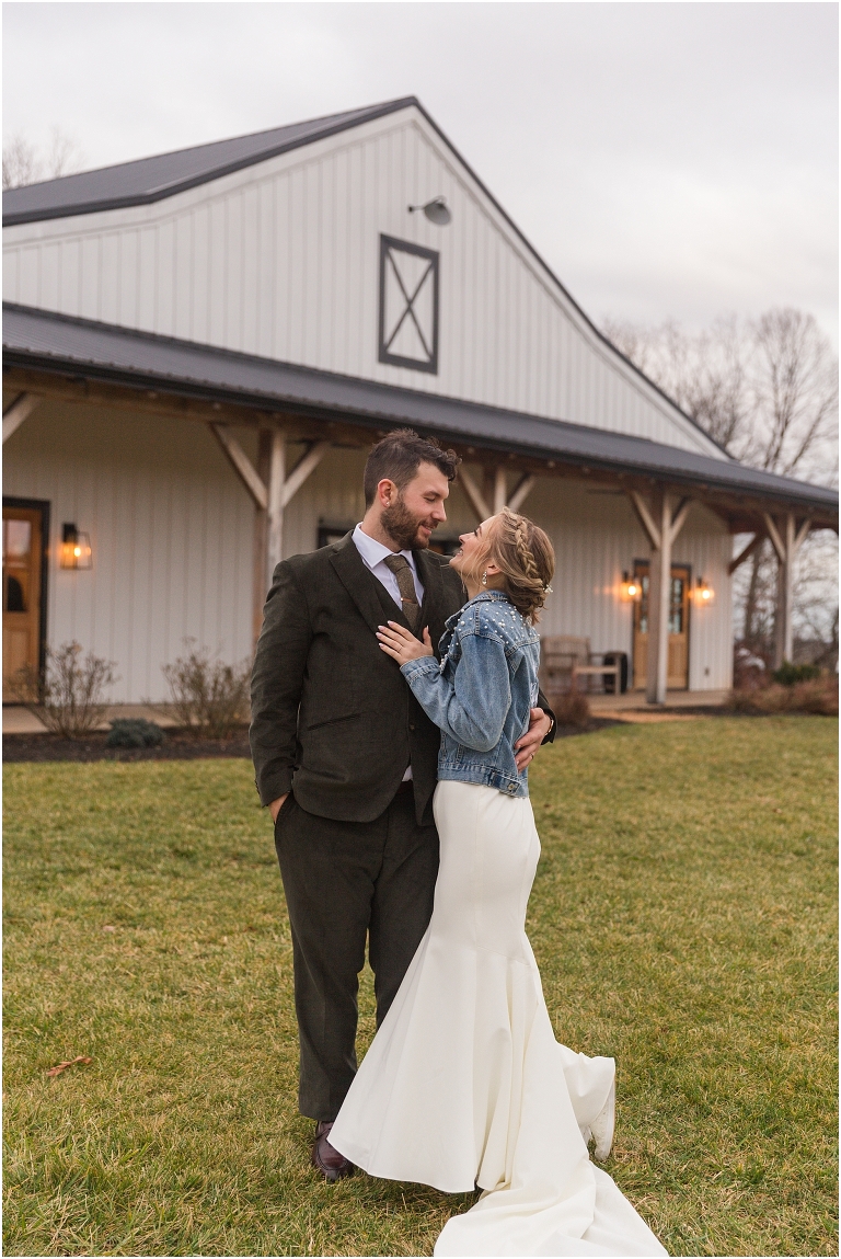 Kristin & Casey's green corduroy winter white barn wedding at Renback Barn with a custom wedding name sign, mountain view wedding portraits, all black wedding party clothes, wedding jean jacket, and sparkler exit.
