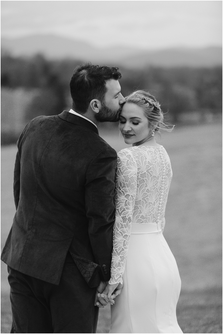 Kristin & Casey's green corduroy winter white barn wedding at Renback Barn with a custom wedding name sign, mountain view wedding portraits, all black wedding party clothes, wedding jean jacket, and sparkler exit.