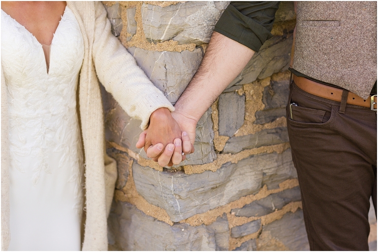 Family farm and barn spring wedding first touch between bride and groom around a brick and wood shed