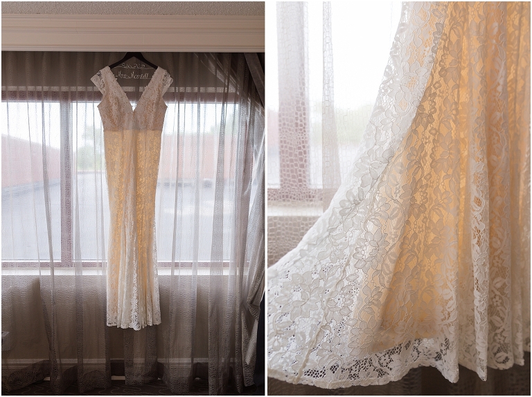 A lacy wedding dress hanging from a customized hanger while the bride gets ready in her hotel room for her Virginia elopement